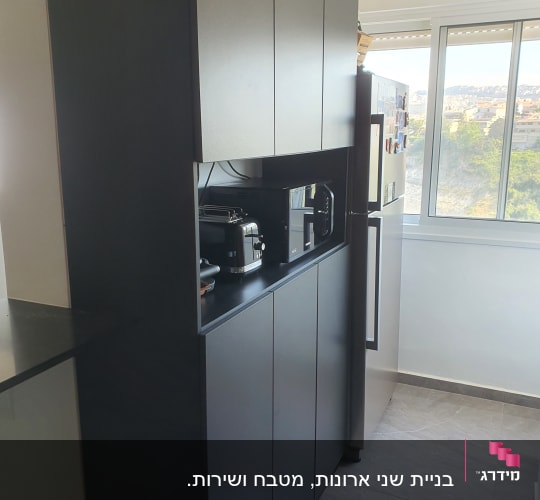 ארונות מטבח כהים עם מכשירי חשמל על מדף